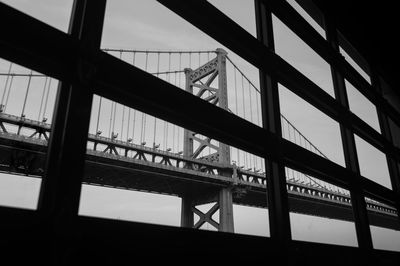 Low angle view of bridge seen through window against sky