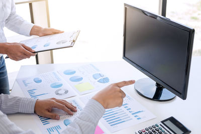 Midsection of businessman and colleague working over graph on table