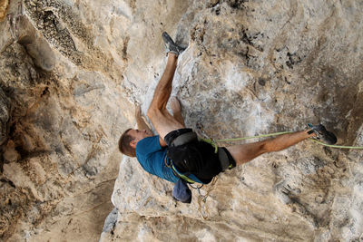 Midsection of man with arms raised on rock