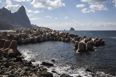 Tetrapod rocks in sea against sky