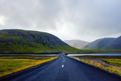 Road leading towards mountains against sky