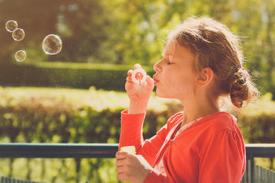 Close-up of girl blowing bubbles at park