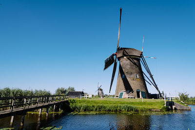 Traditional windmill by river against blue sky at kinderdijk