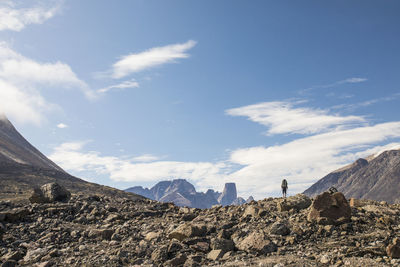 Hiker on distant mountain ridge looking at mountain view.