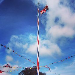 Low angle view of british flag waving amidst bunting flags against blue sky