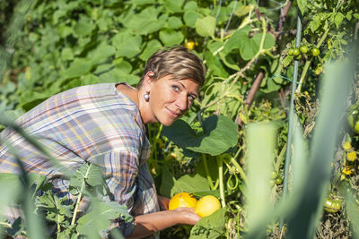 Portrait of smiling woman holding fruits at farm