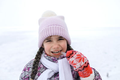 Portrait of smiling girl biting ice during winter