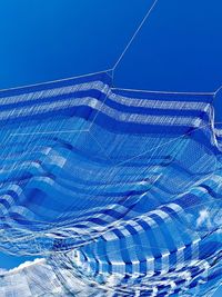 Low angle view of glass structure against blue sky