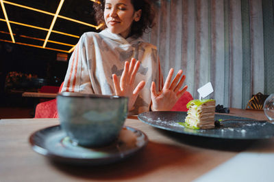 Midsection of woman with drink sitting on table