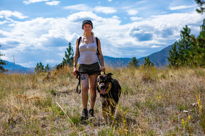 Man with dog on field against sky