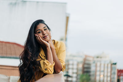 Portrait of smiling young woman against built structure