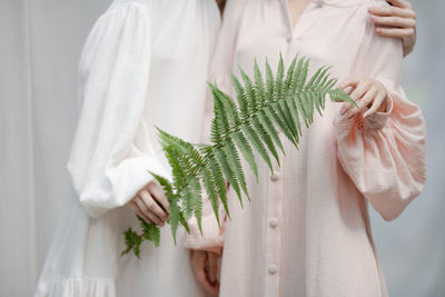 Midsection of women standing with plant