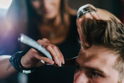 Close-up of woman cutting man hair