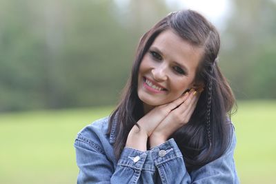 Portrait of smiling young woman against trees