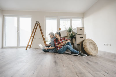 Couple sitting on floor of their new home among moving boxes
