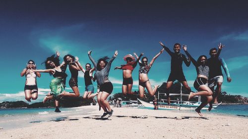 People jumping on beach against sky