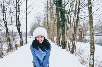 Portrait of smiling woman standing on snow covered land