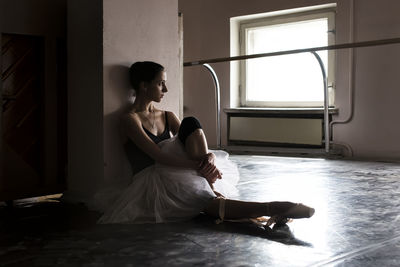 Full length of young ballet dancer sitting on floor
