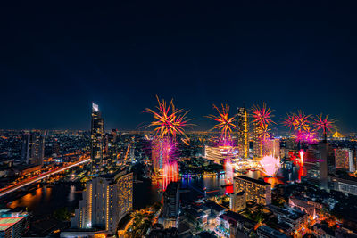 Firework display over city lit up at night. high angle view of illuminated buildings 