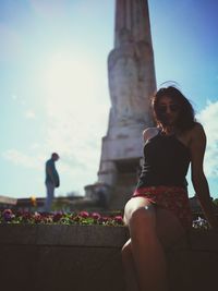 Low angle view of woman sitting against sky