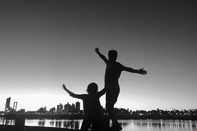 Silhouette man and woman standing in water against clear sky