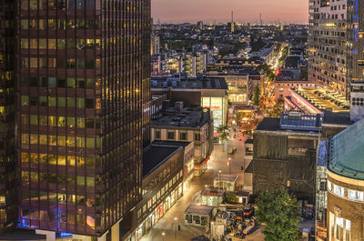 High angle view of illuminated street amidst buildings in city at night