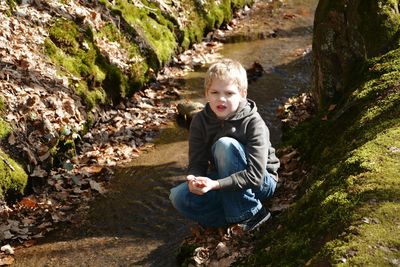 Portrait of boy crouching at stream