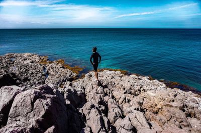 Man standing on rock against sea at beach