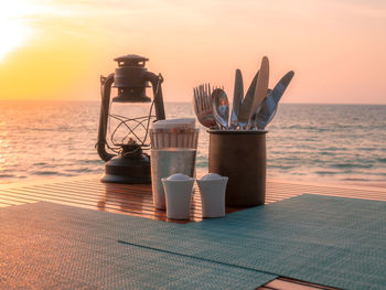 Dining table at beach against sky during sunset