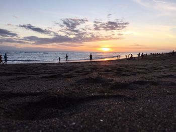 People walking on beach at sunset
