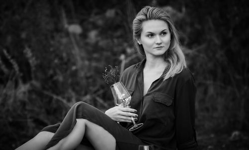 Portrait of woman holding ice cream sitting outdoors