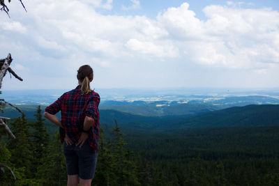 Rear view of man standing on mountain against sky