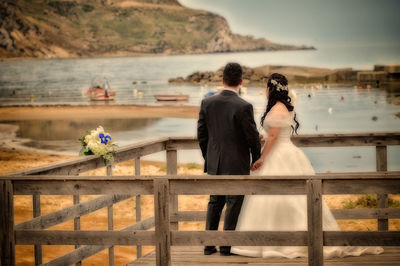 Rear view of couple standing against sea