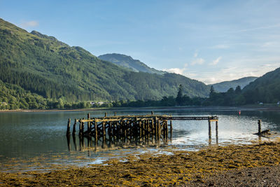 Wooden posts in lake against sky