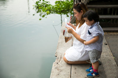 Full length of mother with son holding fish at lake