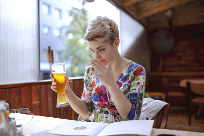 Midsection of woman drinking glass on table at restaurant