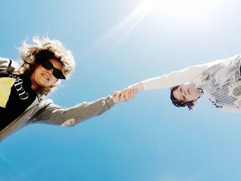 Low angle view of friends against blue sky