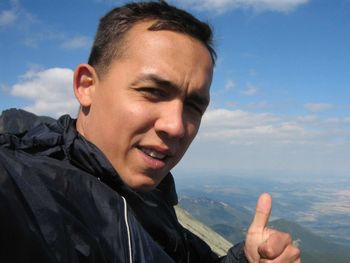 Close-up portrait of man gesturing thumbs up against landscape