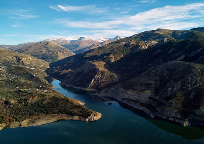 Aerial view of lake by mountains against sky