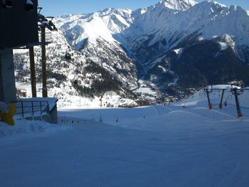 Ski lift over snowcapped mountains against sky