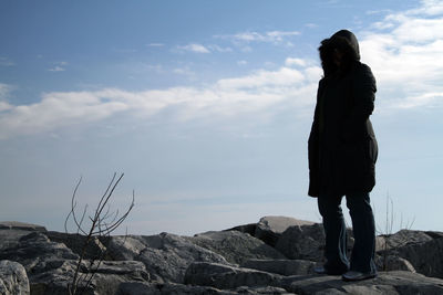 Man standing on rock against sky
