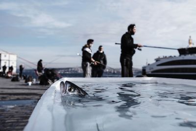 People on boat in sea against sky