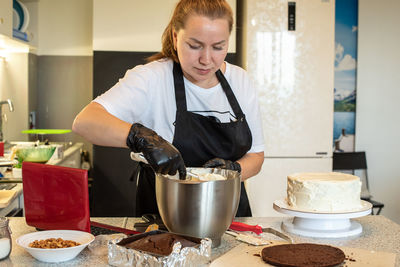 Blogger pastry chef cook confectioner  makes a cake. woman in apron using notebook while cooking. 