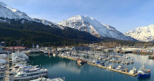 Sailboats moored at harbor against sky during winter