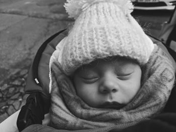 Close-up high angle view of cute baby boy wearing warm clothing while sleeping outdoors