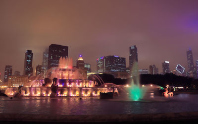 Illuminated buildings in city against sky at night