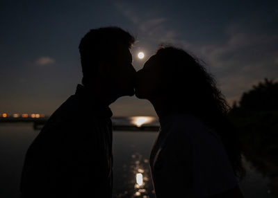 Silhouette couple kissing against sky