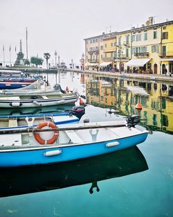 Boats moored at harbor against buildings in city