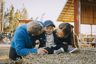 Parents looking at son sitting on hay bale