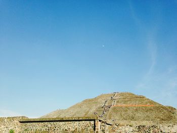 Low angle view of landscape against clear blue sky